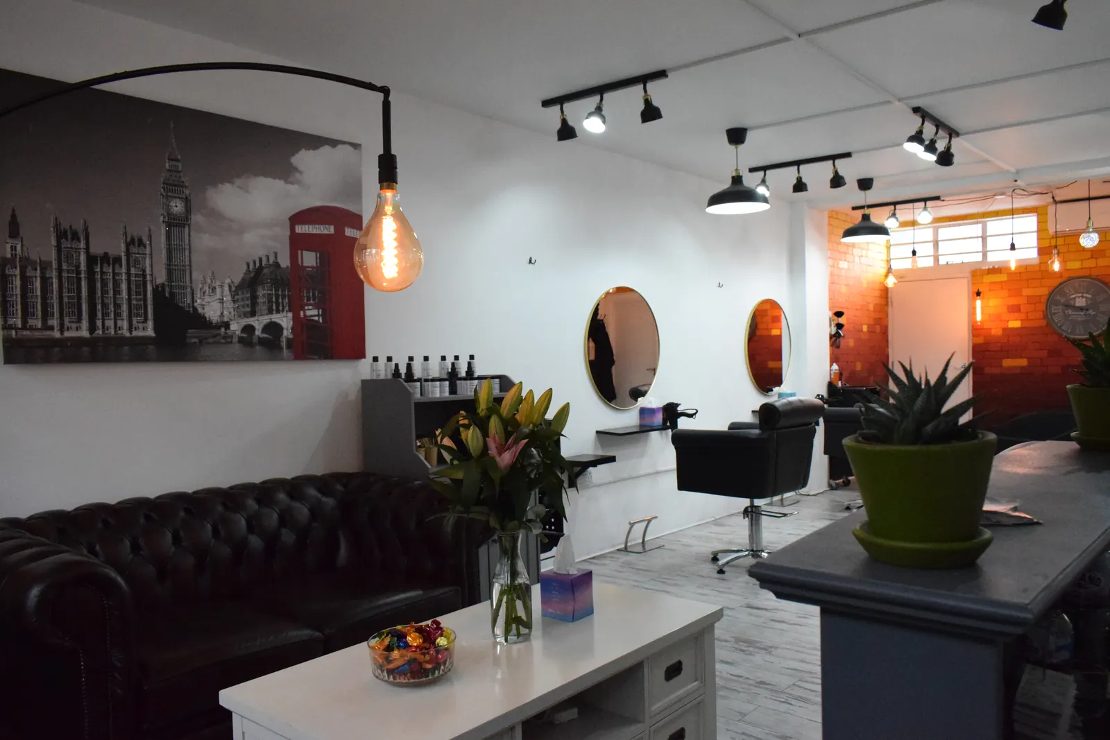 Inside SEoneHair near London Bridge: chesterfield sofa, red phone box and Big Ben print, Edison bulb lamp